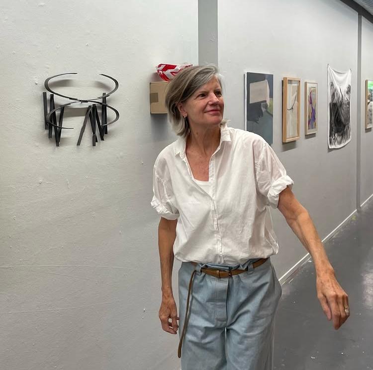 Ine Boeijen in een expositieruimte, naast een van haar wandbeelden